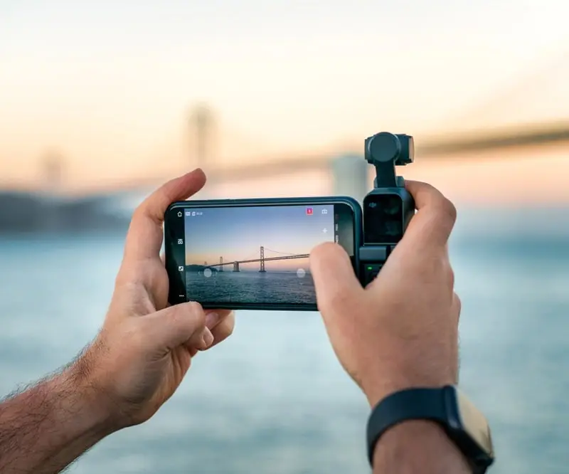 A smartphone recording video being held up by two hands.